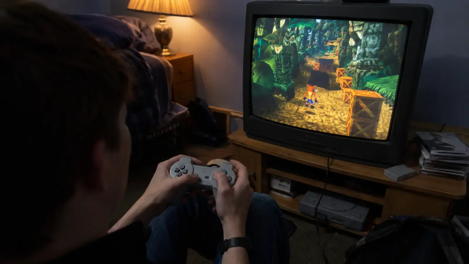 Adolescente jugando un plataformas 3D de selva en un televisor CRT con un mando gris.