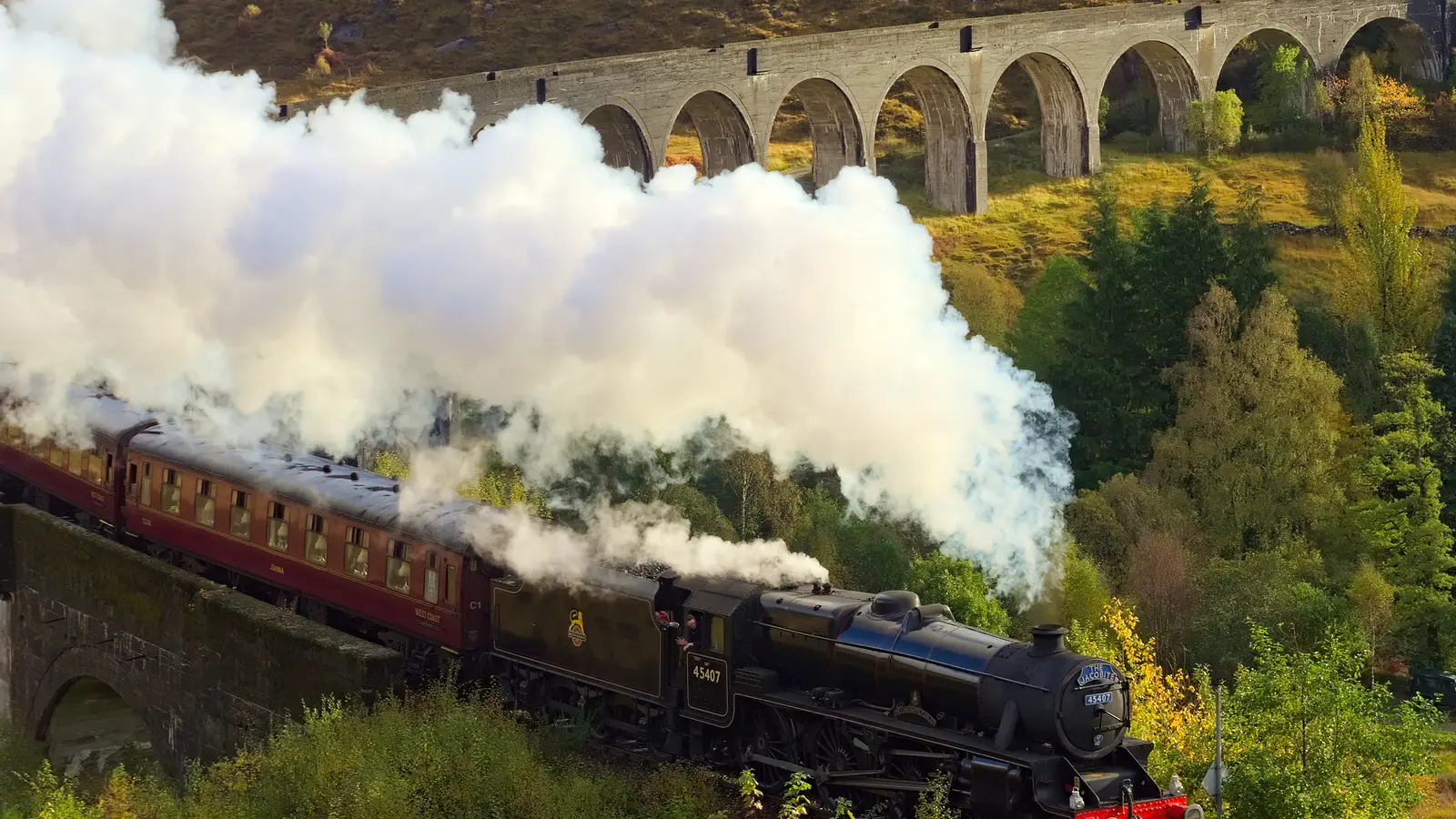 Tren de vapor Jacobite cruza el viaducto de Glenfinnan entre montañas escocesas