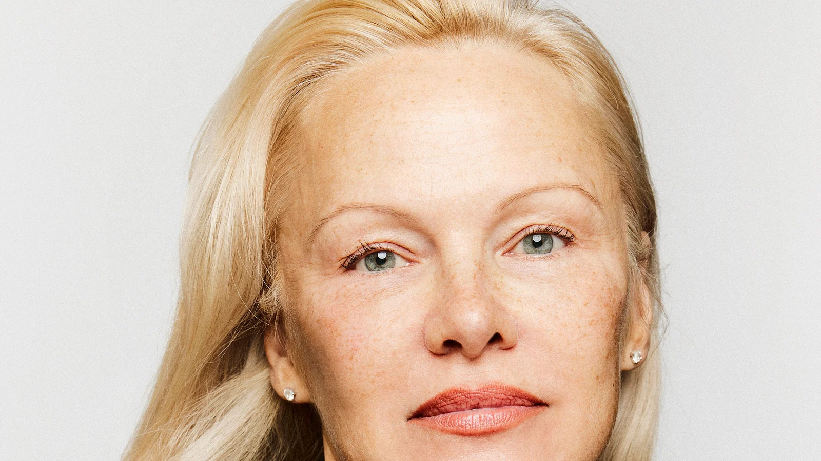 Primer plano de Pamela Anderson frente a un fondo blanco en un retrato de 2024.