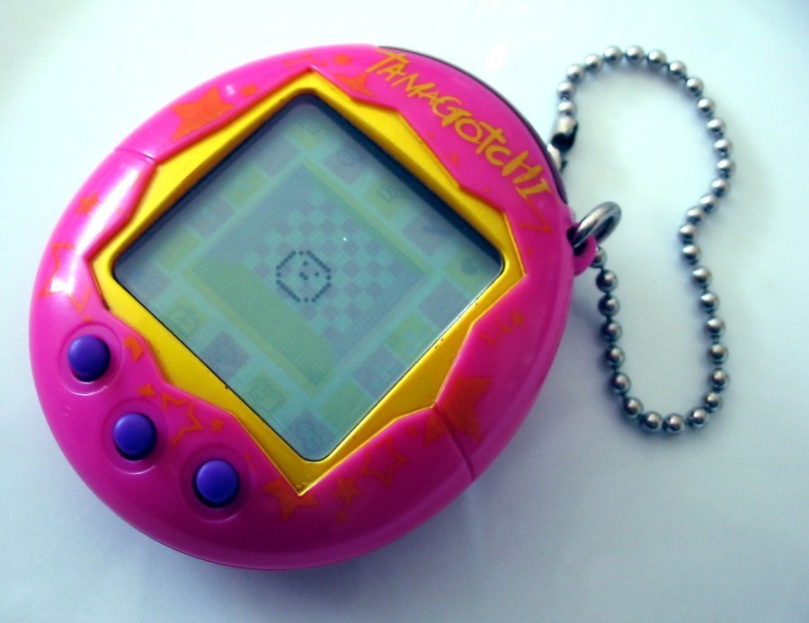 A pink and yellow Tamagotchi with three purple buttons and a ball chain